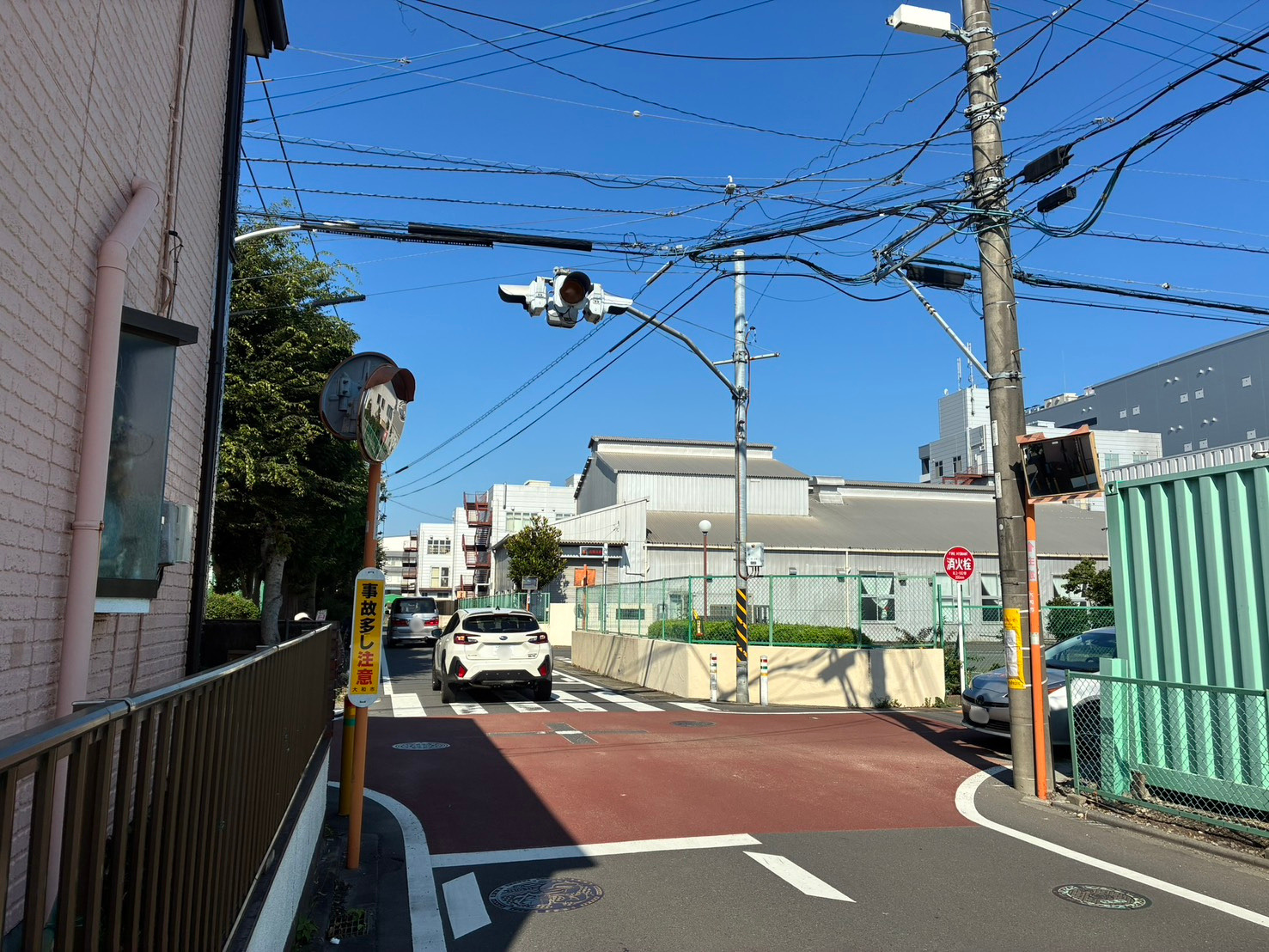 大和市内の交差点。一灯点滅式の信号、「事故多し注意」の標識、赤い舗装、カーブミラーが確認できる